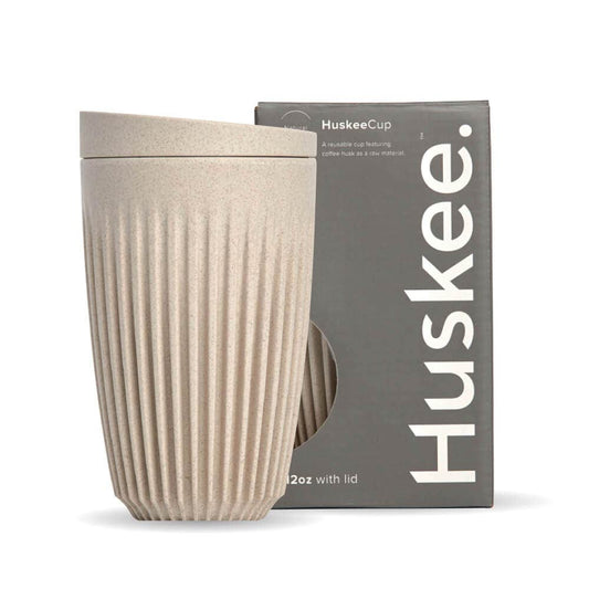 12oz Natural Huskee Reusable Coffee Cup with Lid in front of its packaging box