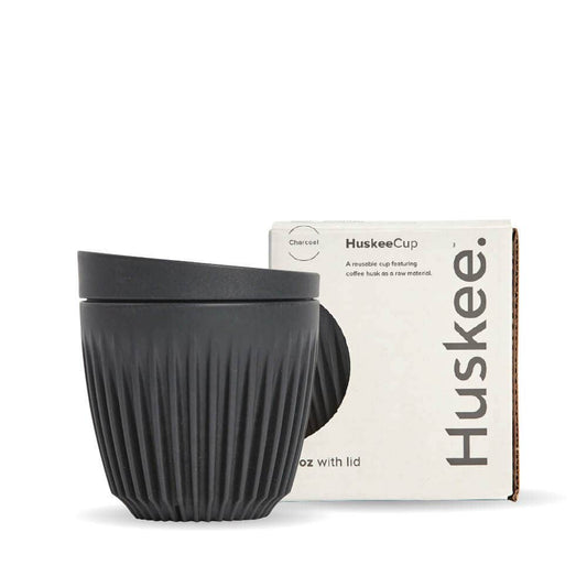 6oz Charcoal Huskee Reusable Coffee Cup with Lid in front of its packaging box