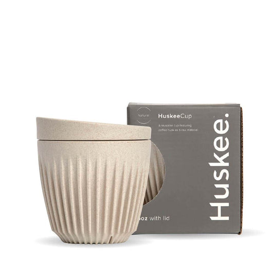 6oz Natural Huskee Reusable Coffee Cup with Lid in front of its packaging box
