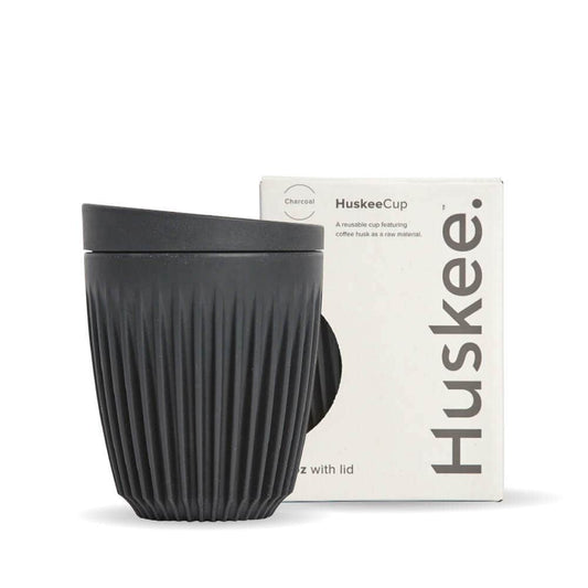 8oz Charcoal Huskee Reusable Coffee Cup with Lid in front of its packaging box