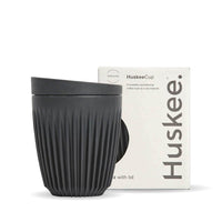 8oz Charcoal Huskee Reusable Coffee Cup with Lid  in front of its packaging box