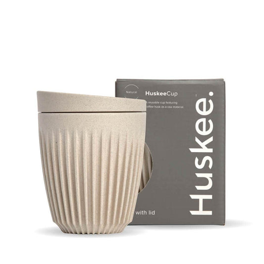 8oz Natural Huskee Reusable Coffee Cup with Lid in front of its packaging box